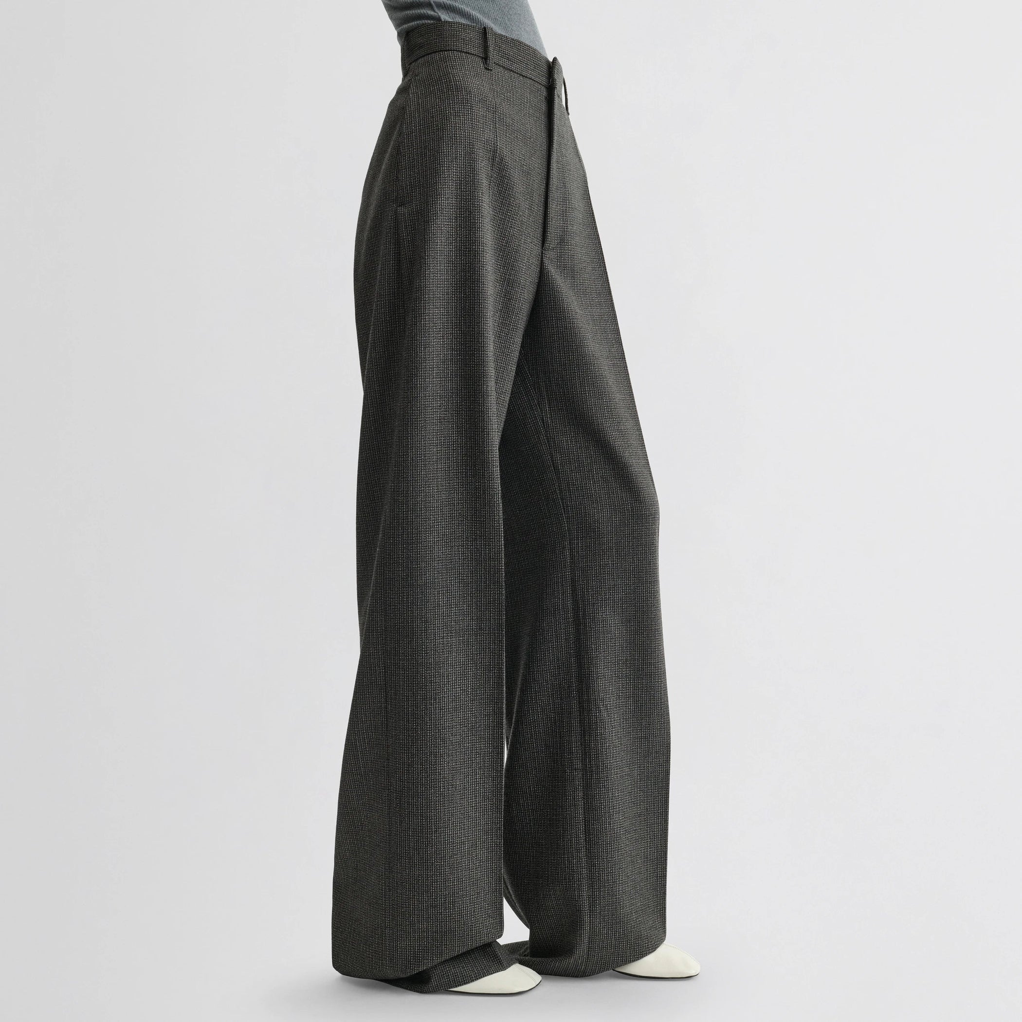 Side view of model wearing zip trousers in green bronze wool.