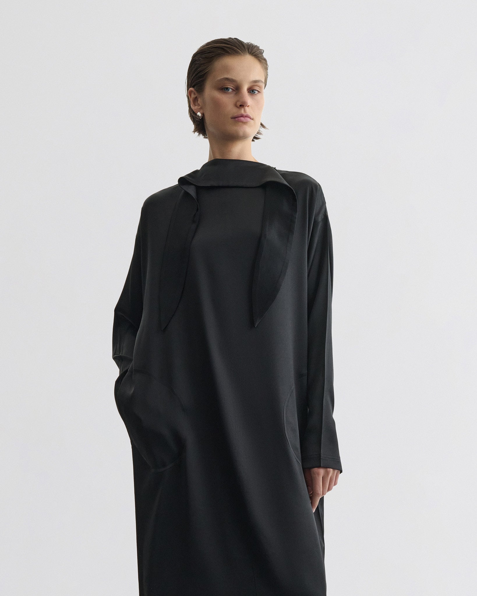 Front view of model wearing liquid high neck dress in black silk.
