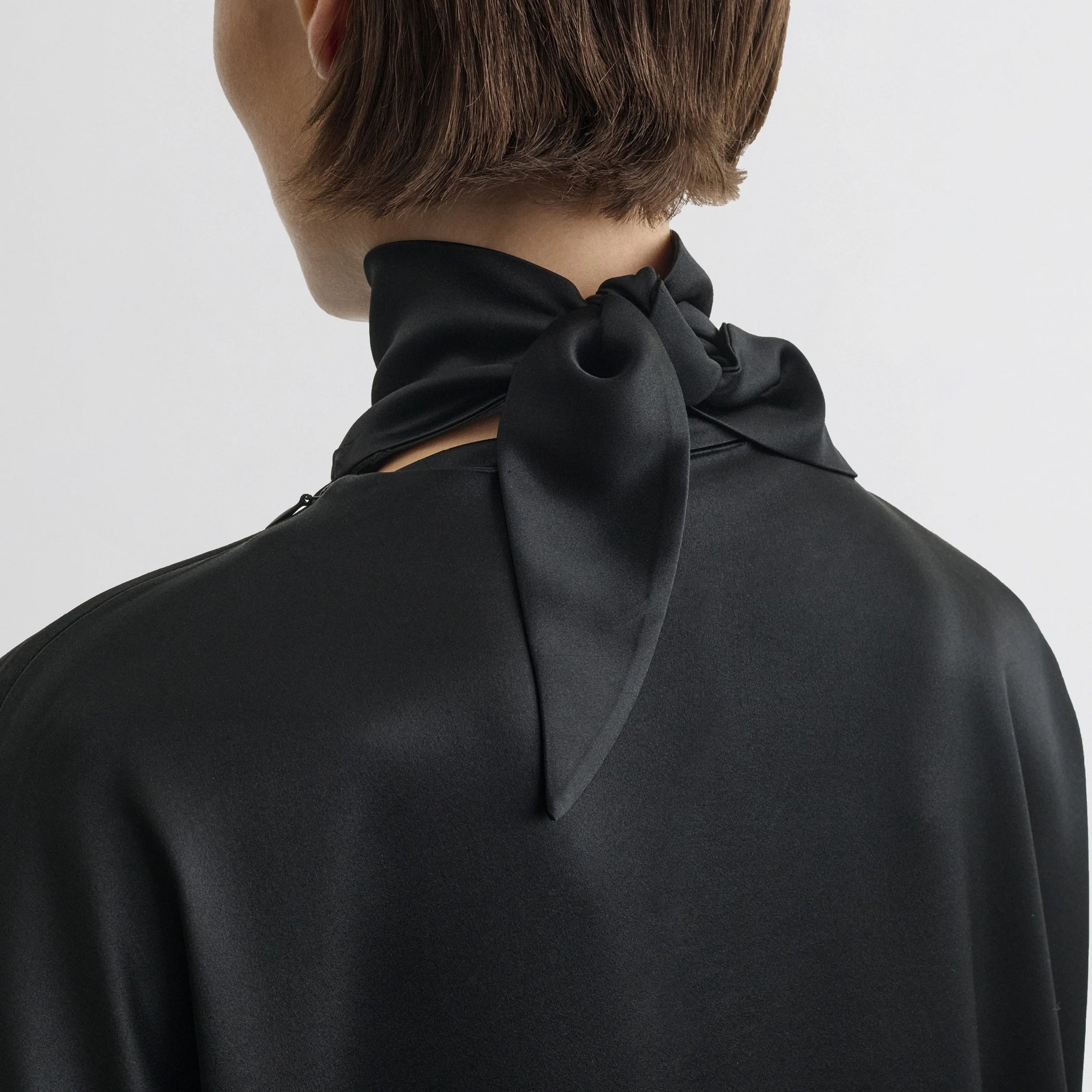 Close up detail view of liquid knot collar top in black silk.