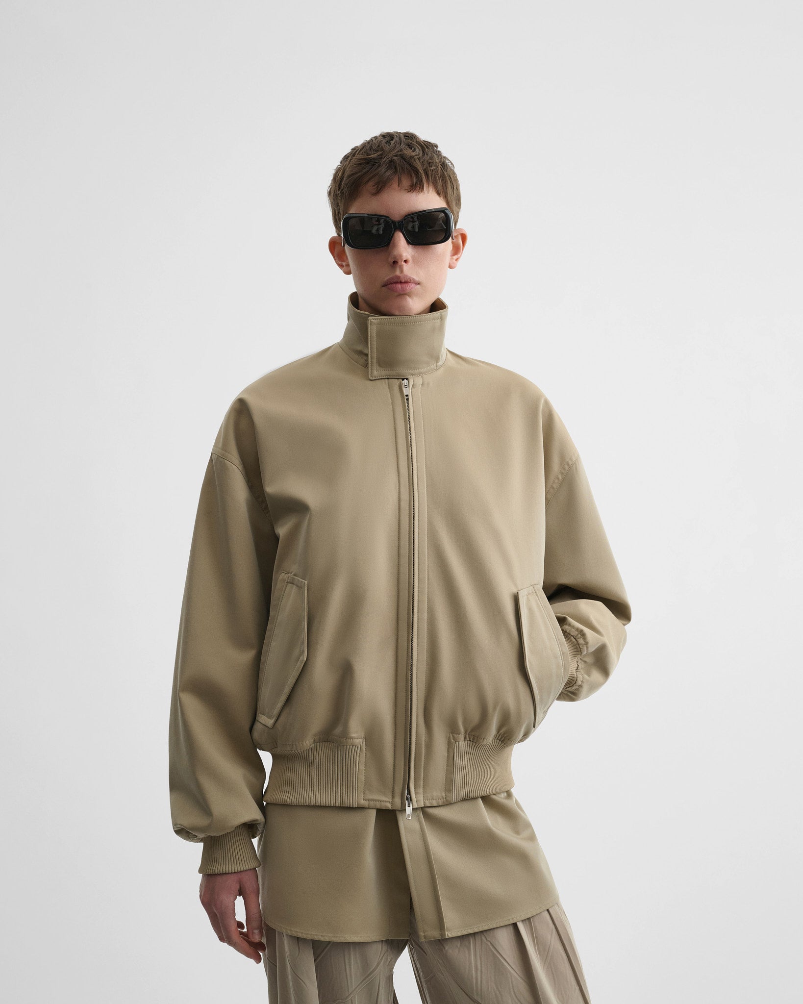 Front view of model wearing golf jacket in trench cotton.