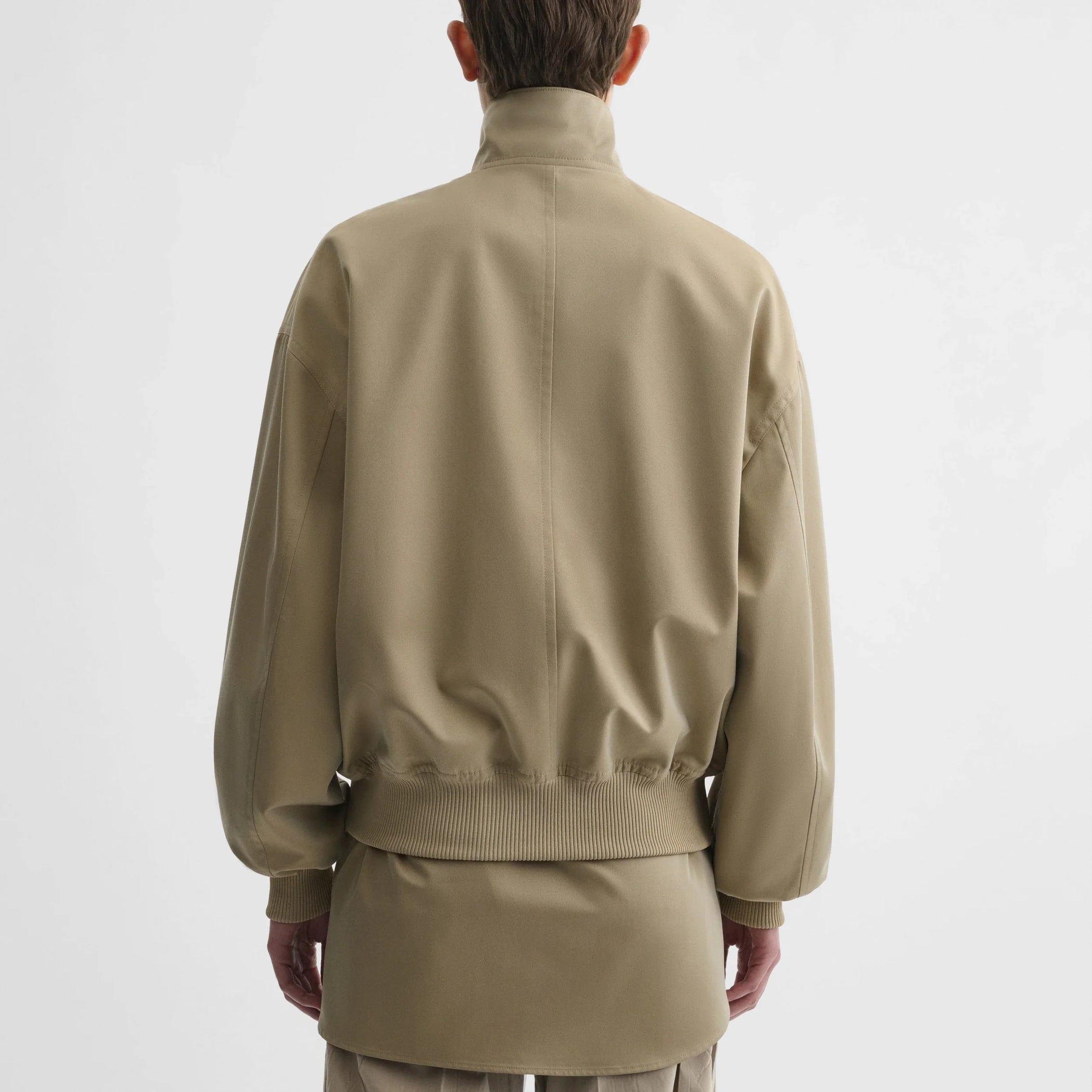 Back view of model wearing golf jacket in trench cotton.