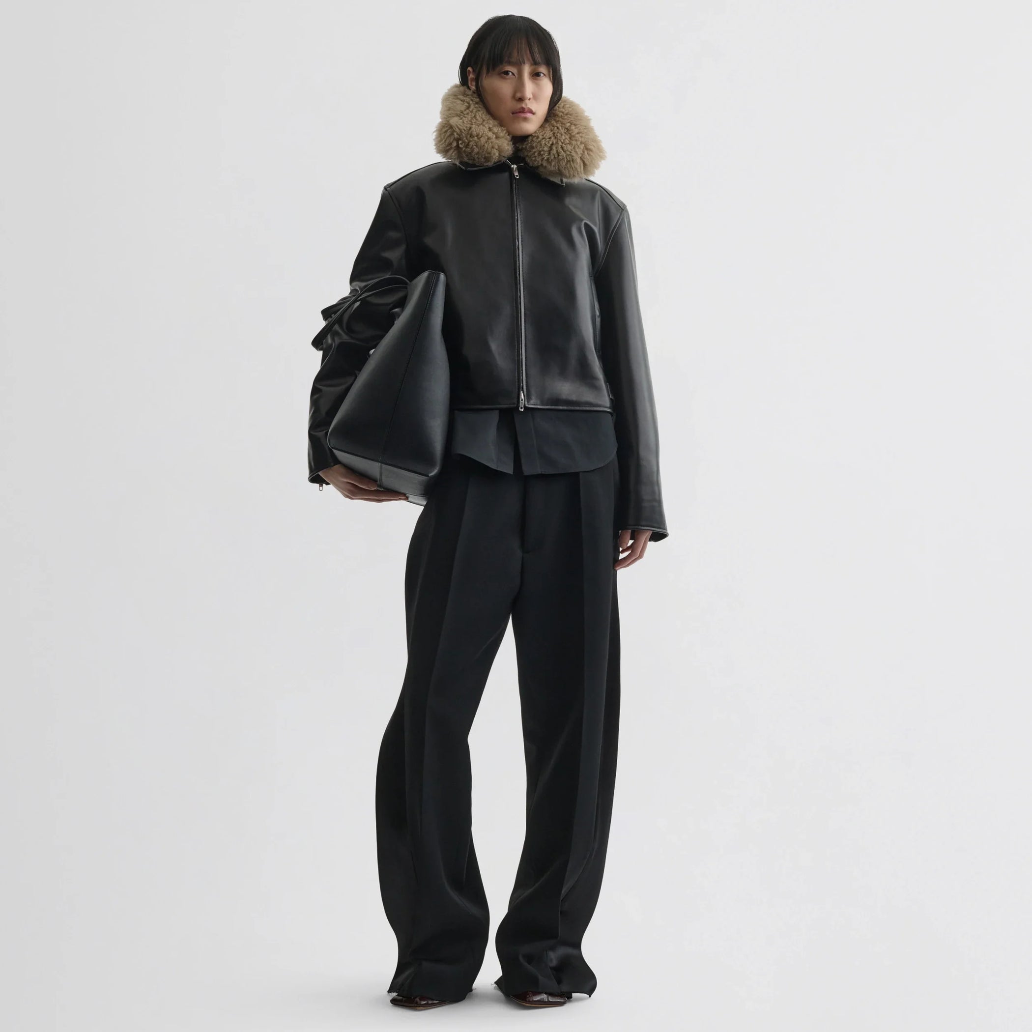 Front view of model wearing cropped aviator jacket in black leather.