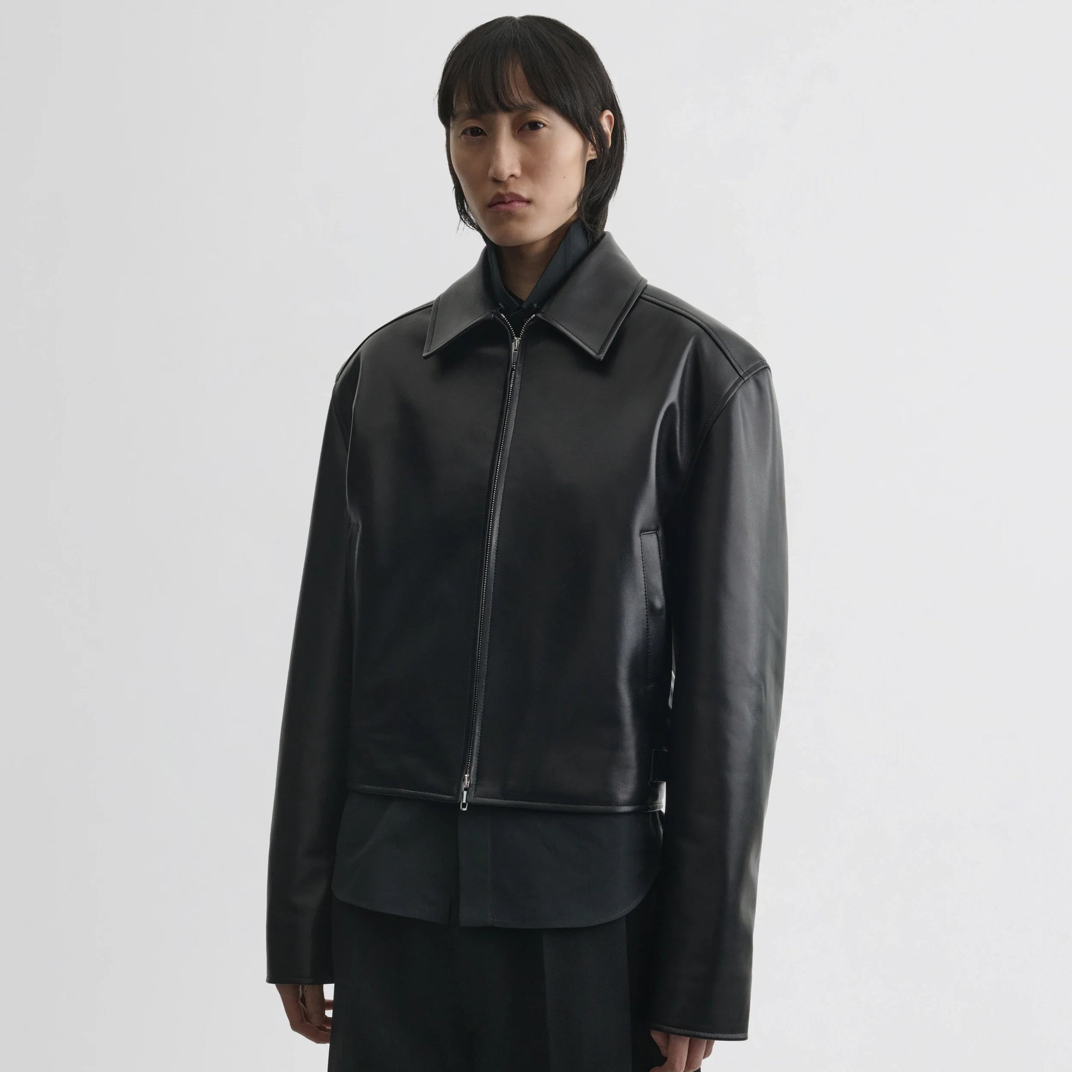 Front view of model wearing cropped aviator jacket in black leather.