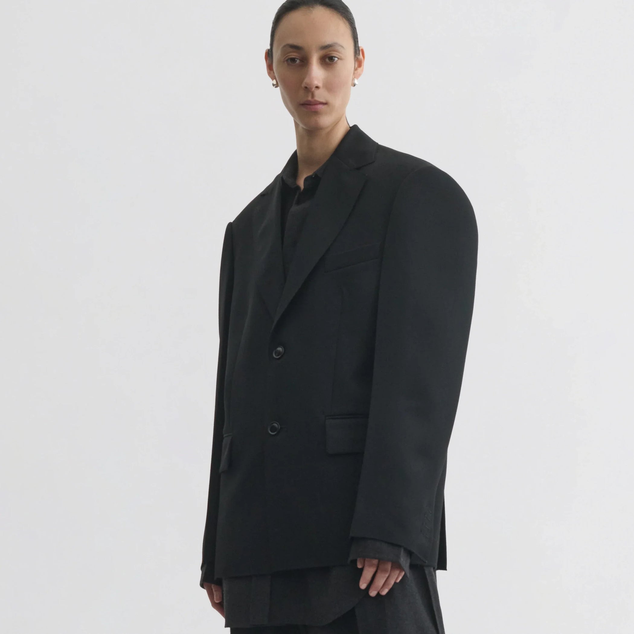 Front view of model wearing tuxedo jacket in black wool.