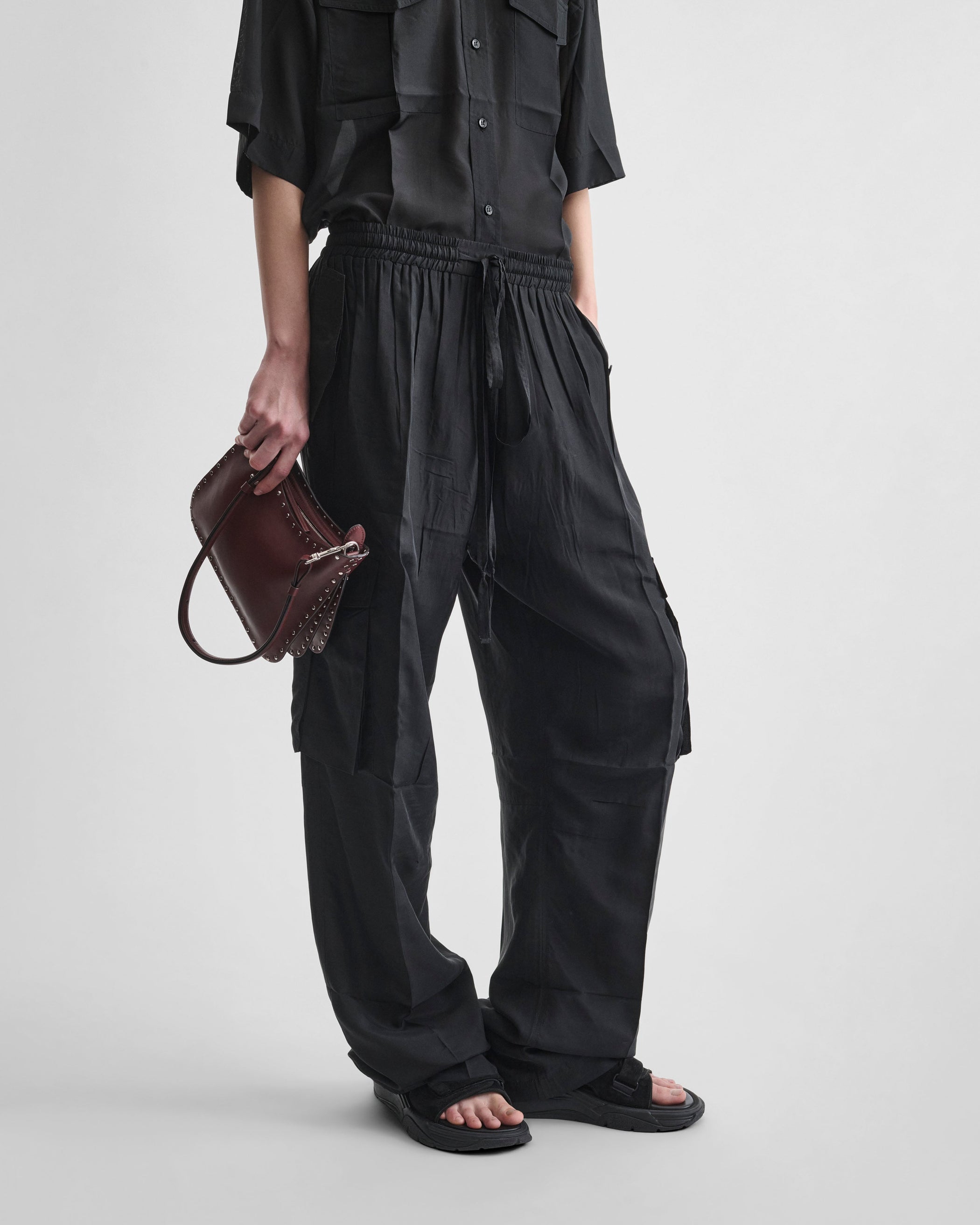 Front view of model holding SMALL STUD GIG BAG in chestnut leather