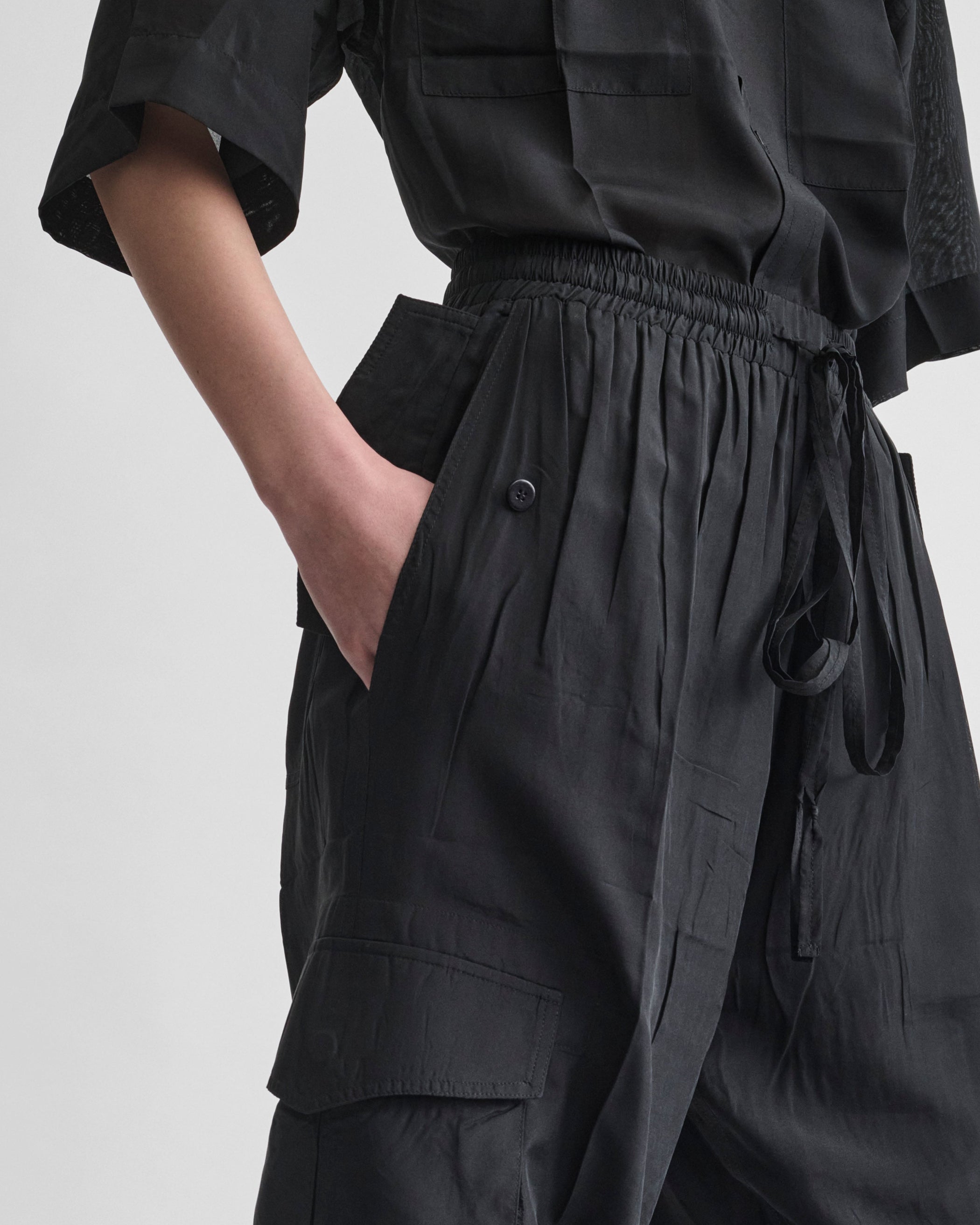 Detail view of model wearing CARGO TROUSERS in black silk