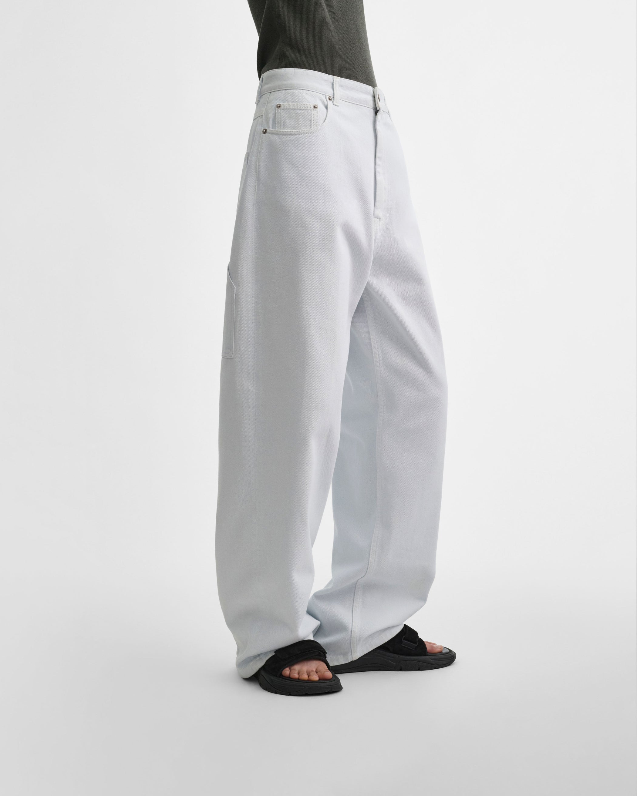 Side view of model wearing RELAXED ZIP JEANS in pale ice blue cotton