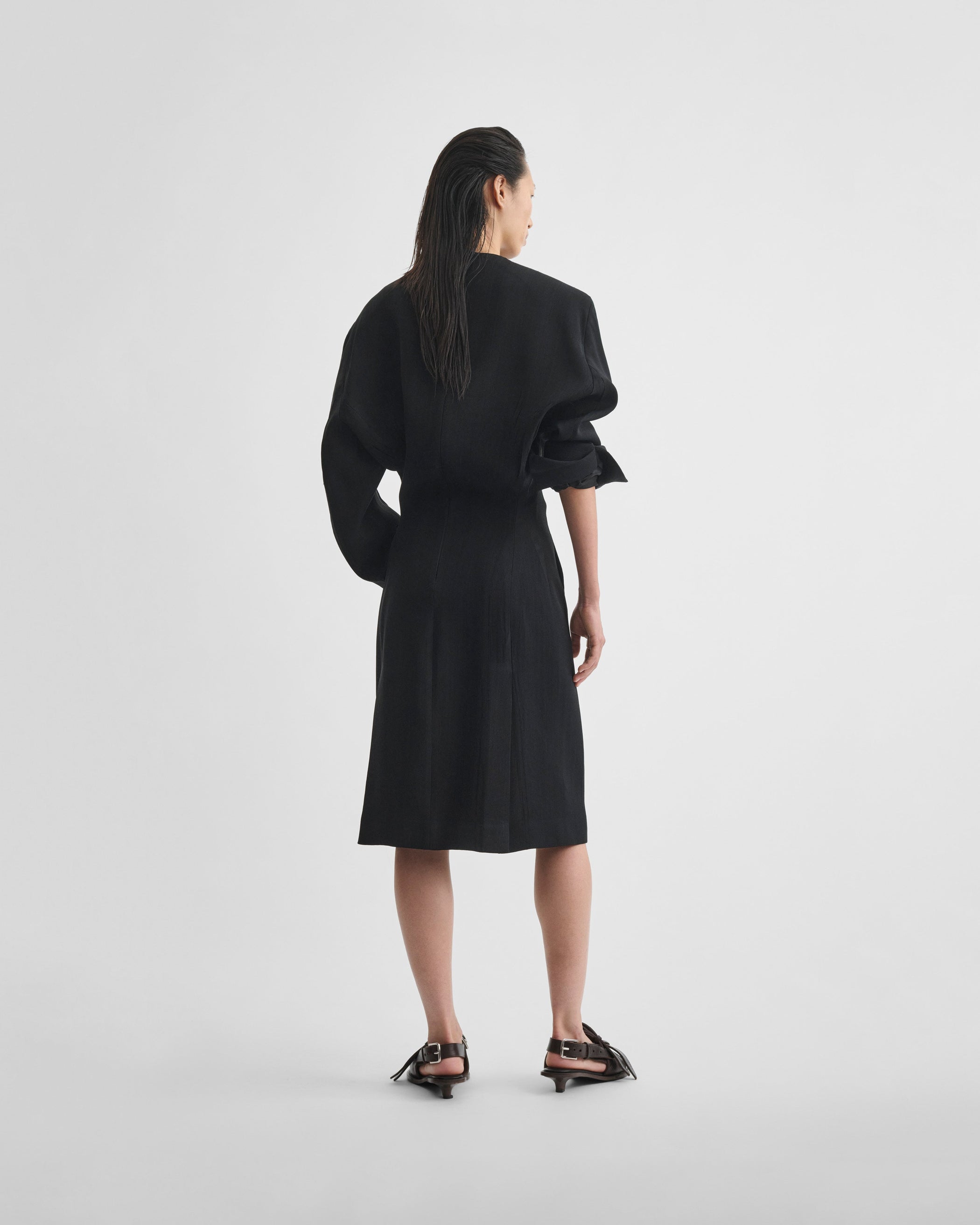 Back view of model wearing KINKED TAILORED DRESS in black viscose