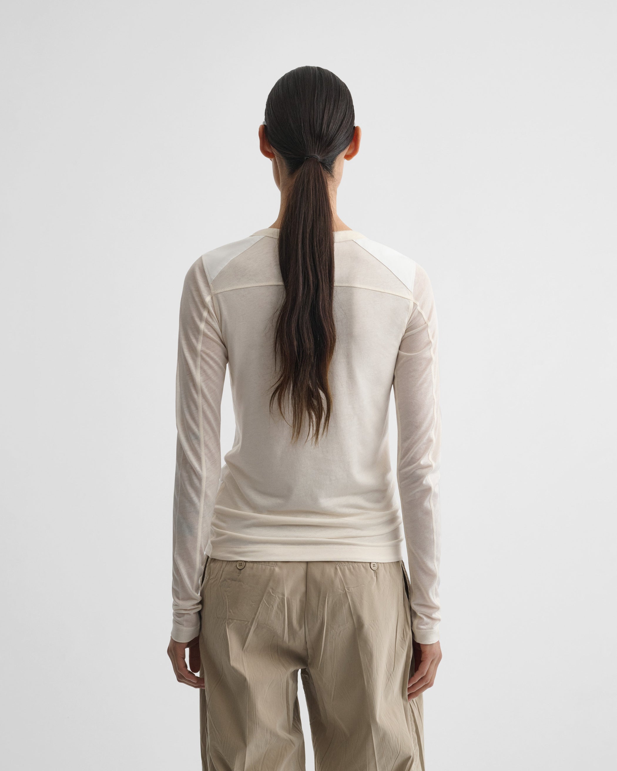 Back view of model wearing CREW NECK TOP in cream cotton