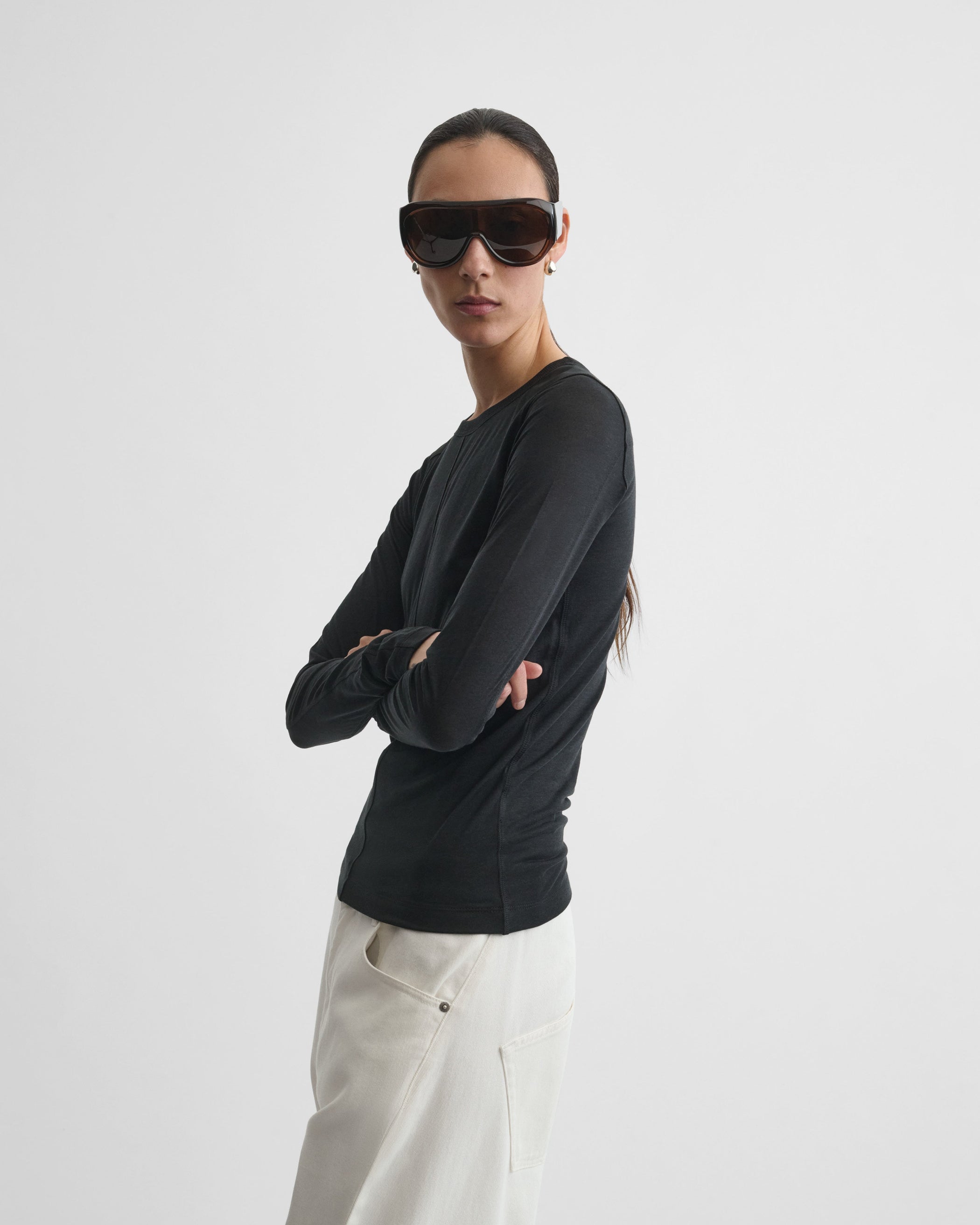 Angled front view of model wearing CREW NECK TOP in black cotton